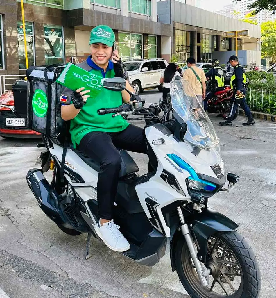 A GO21 courier on a motorcycle holding a packaged envelope