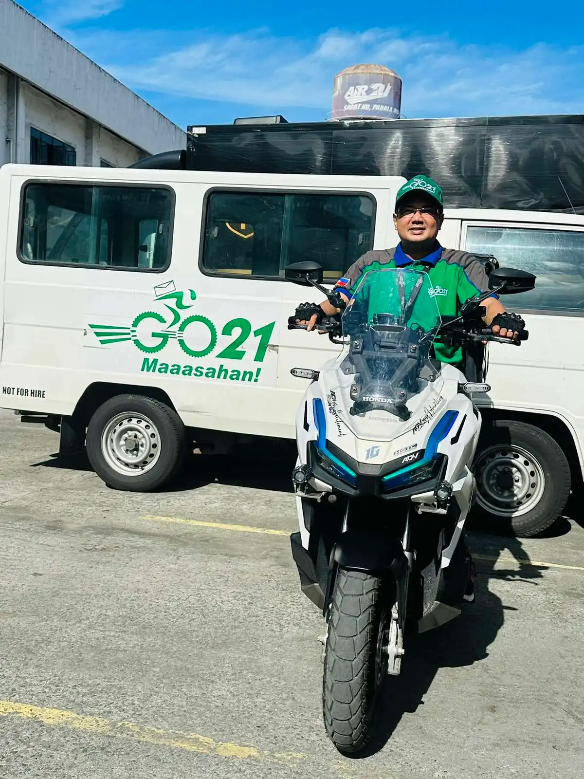 A GO21 courier on a motorcycle in front of a GO21 truck