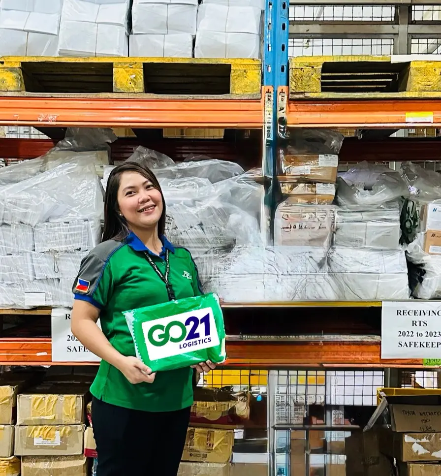 Two GO21 employees holding a package in front of a shelf full of goods in a warehouse
